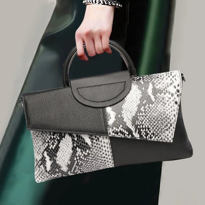 Handbag with black and snake print design held by a person