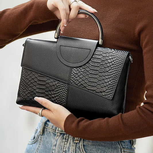 Person holding a black handbag with a textured pattern