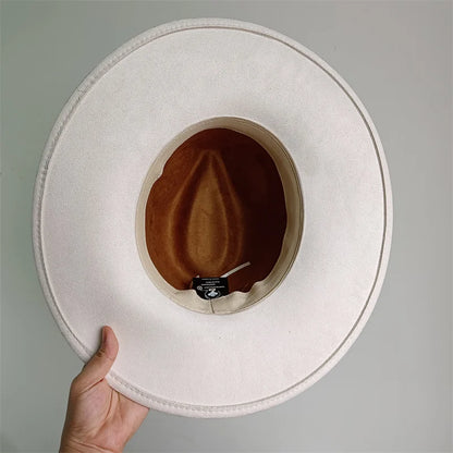 White wide-brimmed hat held by a hand against a gray background