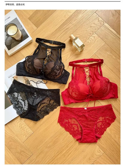 Red and black lace lingerie set on a wooden floor with a candle and book in the background.