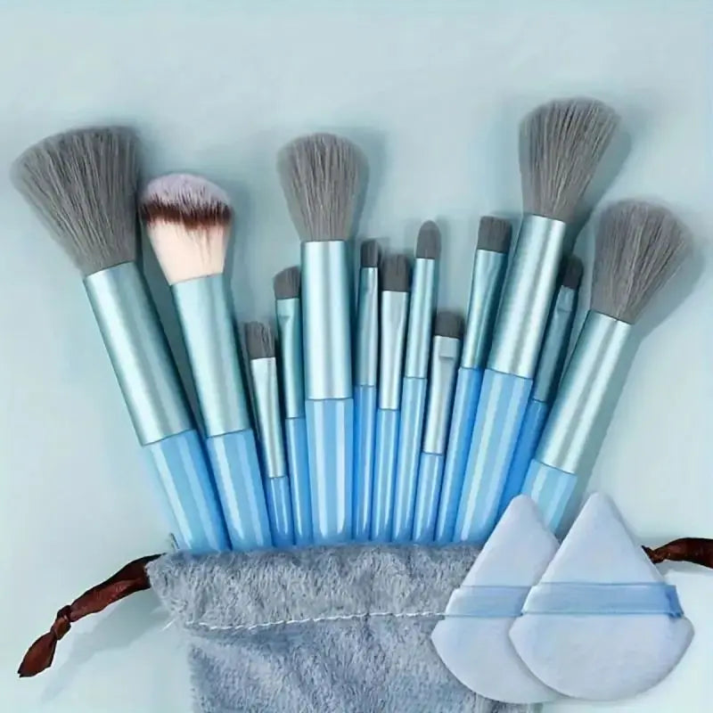 Set of makeup brushes with blue handles and gray bristles on a light gray background. Soft fluffy makeup brush set with wool fiber bristles and plastic handles. Complete set for powder, foundation, eyeshadow, and beauty blending.