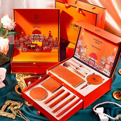 Orange gift set with stationery items on a decorative surface. Christmas makeup gift box with BB cream, lipstick, eyeshadow, eyebrow pencil, and brushes. Holiday beauty set for women & girls.