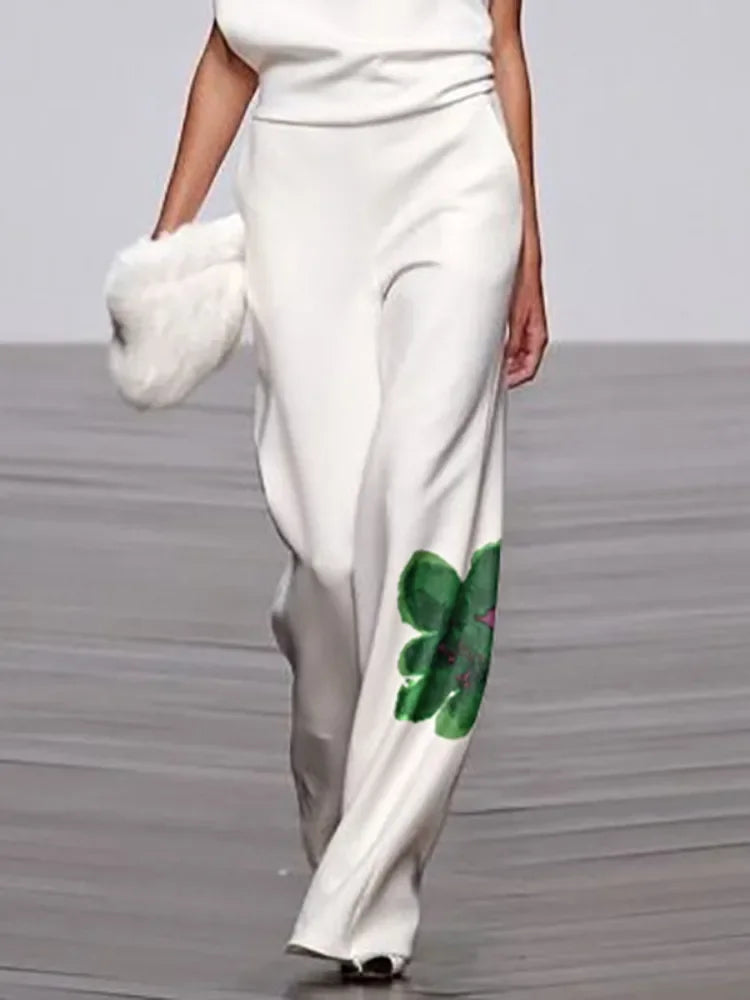 White pants with a green floral design worn by a model on a runway.