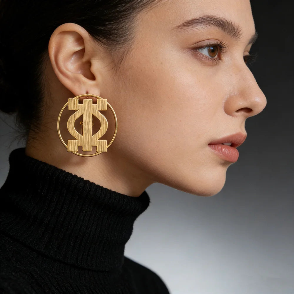 Close-up of large gold hoop earrings with geometric African motif on woman