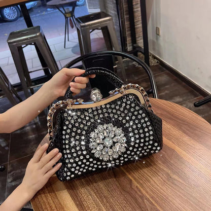 Black handbag with rhinestone embellishments on a wooden table. Large genuine leather dumpling bag with diamond rhinestone clip and lock clasp. Soft handle, multiple compartments. Fashionable shoulder tote for women.