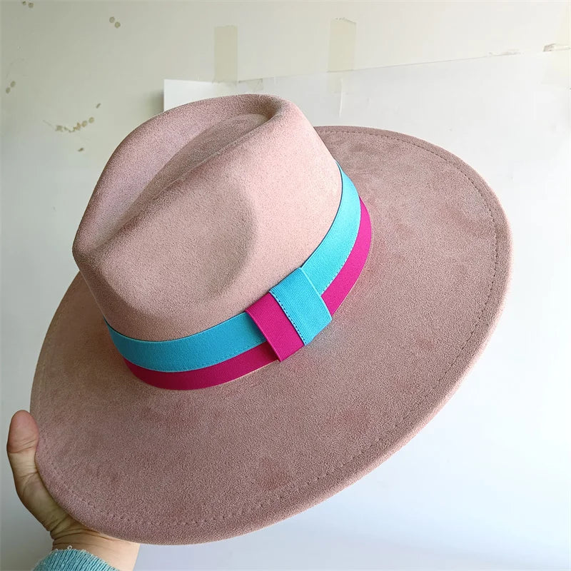 Pink hat with a blue and pink band held by a hand against a light background