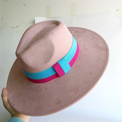 Pink hat with a blue and pink band held by a hand against a light background