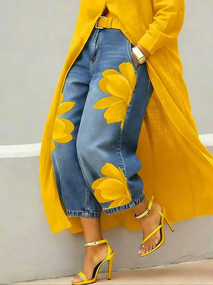 Person wearing a yellow coat with floral patterns, blue jeans, and yellow high-heeled shoes against a neutral background.