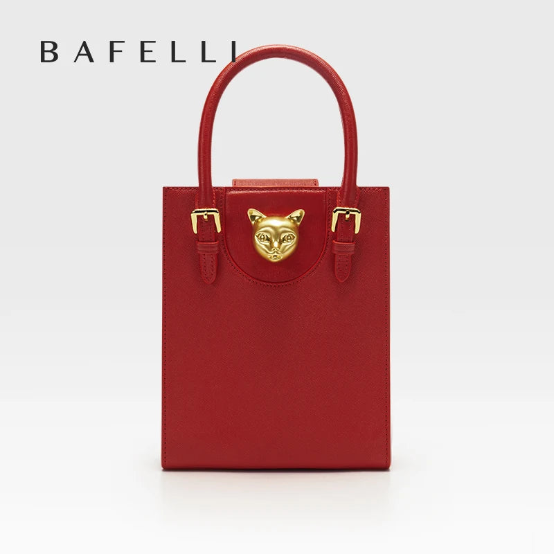 Red handbag with gold accents and a cat face emblem on a white background, featuring the brand 'Bafelli'. Unisex mini tote crossbody bag in split leather with flap pocket and lock closure. Hard box shape and polyester lining. Casual versatile style.
