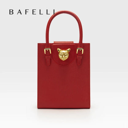 Red handbag with gold accents and a cat face emblem on a white background, featuring the brand 'Bafelli'. Unisex mini tote crossbody bag in split leather with flap pocket and lock closure. Hard box shape and polyester lining. Casual versatile style.