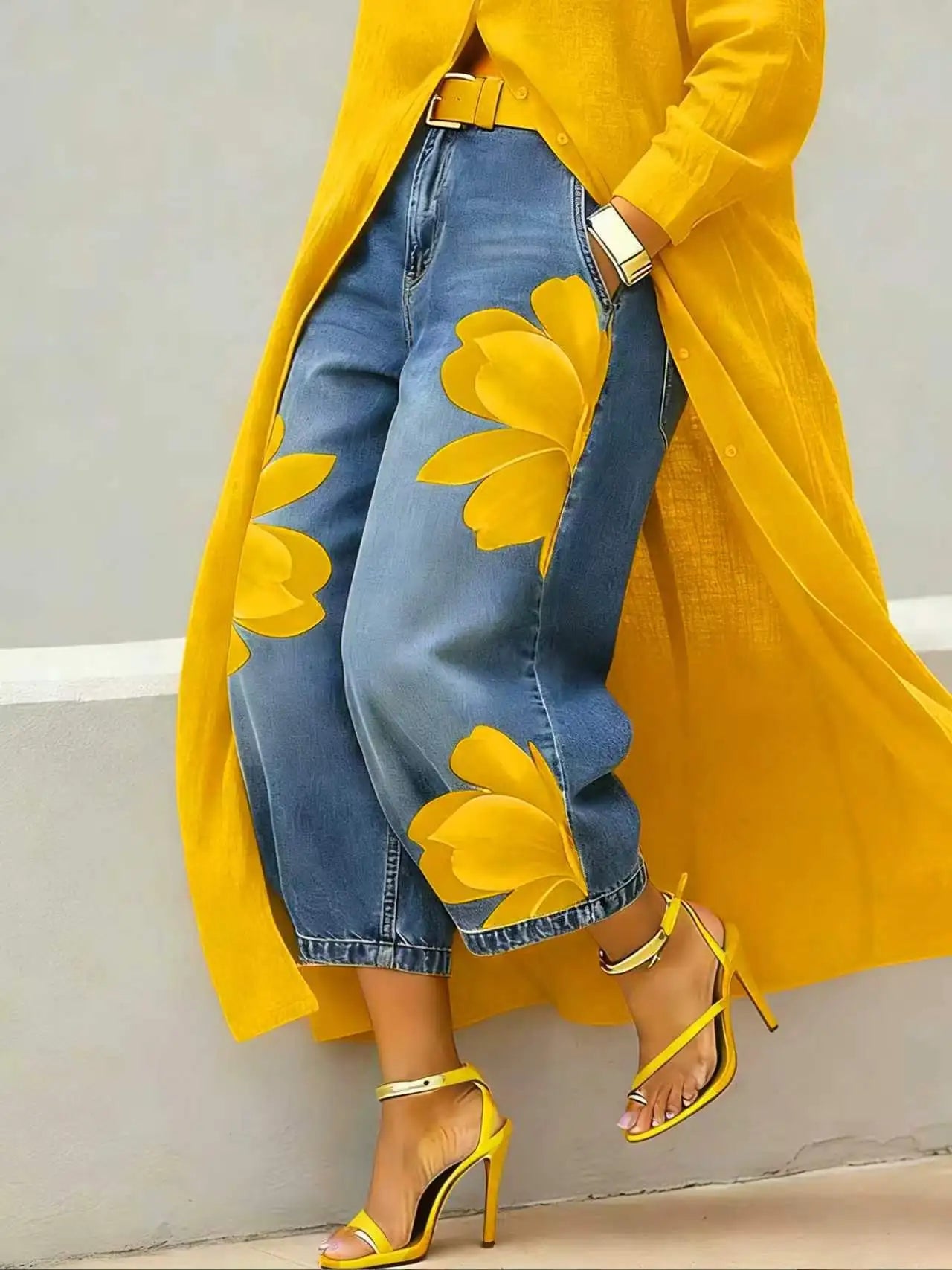 Person wearing a yellow coat with floral patterns, blue jeans, and yellow high-heeled shoes against a neutral background.