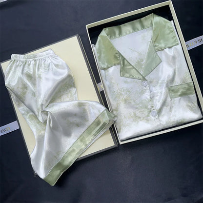 Silk pajama set with shirt and pants in a box on a dark surface. Women’s cherries print summer pajamas set—faux satin V-neck top and shorts, funny cute style. Lightweight, comfortable, UK fashion set.