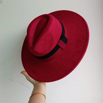 Red hat with a black band held by a hand on a white background