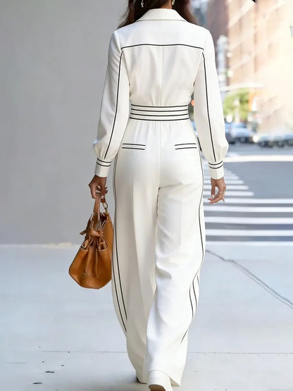 Person wearing a white outfit with black accents walking on a city street.