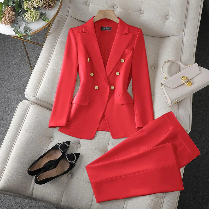 Red suit with gold buttons on a white chair, accompanied by black shoes and a white handbag.