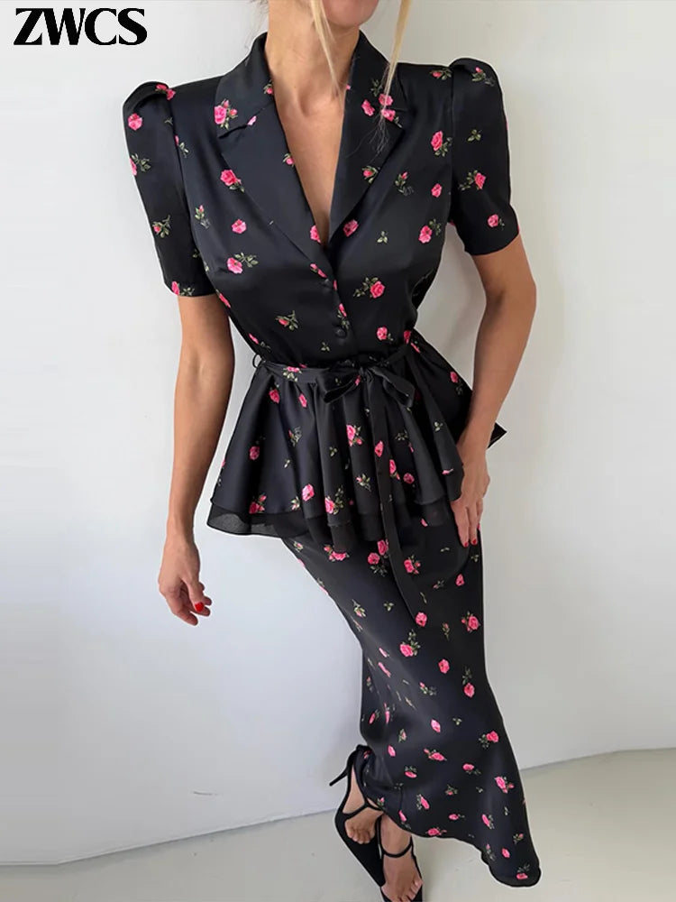 A woman models a black satin-like wrap dress with a pink and green floral print, featuring puff sleeves, a tie waist, and a peplum hem. The brand name 'ZWCS' is visible in the top left corner.