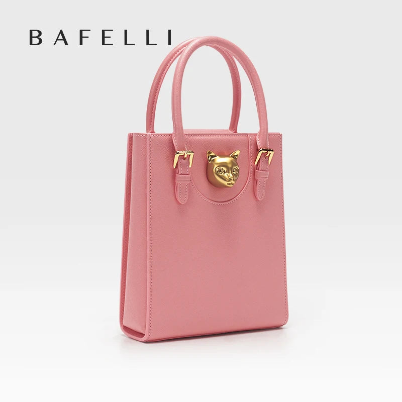 Pink handbag with gold accents on a white background, featuring the brand 'Bafelli'. Unisex mini tote crossbody bag in split leather with flap pocket and lock closure. Hard box shape and polyester lining. Casual versatile style.