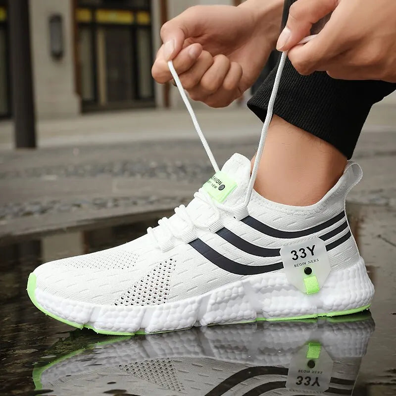 White athletic shoe with black stripes and green accents being worn on a reflective surface.