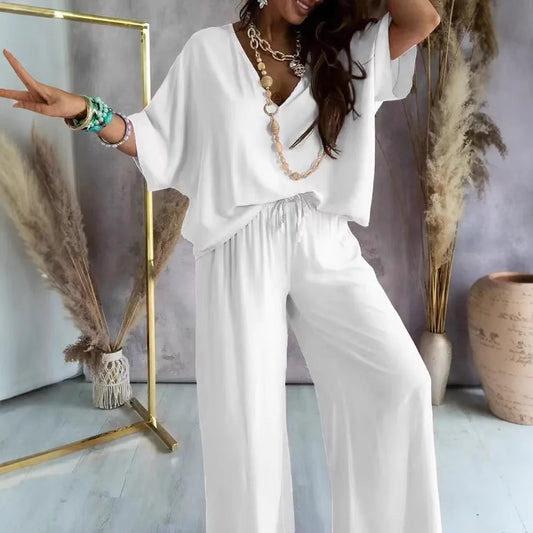 Woman in a white outfit posing in a stylish room with decor elements.