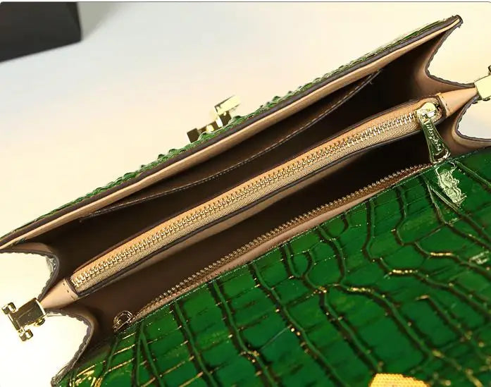 Green handbag with gold accents on a white background. Small genuine leather crocodile crossbody bag. Hard flap design with soft handle, zipper closure, and interior phone & compartment pockets.