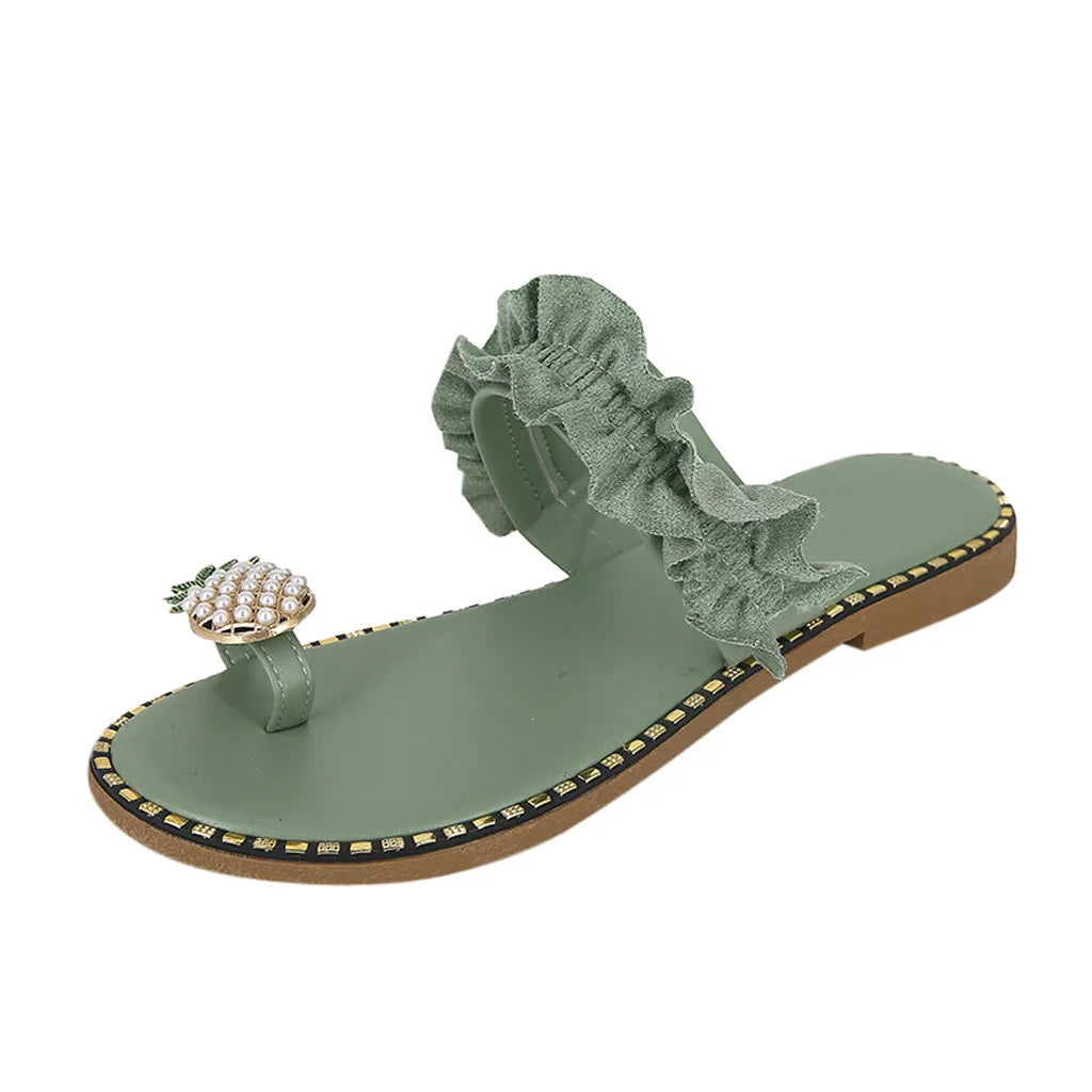 Green sandal with ruffled strap and pineapple charm on a white background