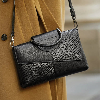 Black textured handbag with a patterned flap over a beige coat.