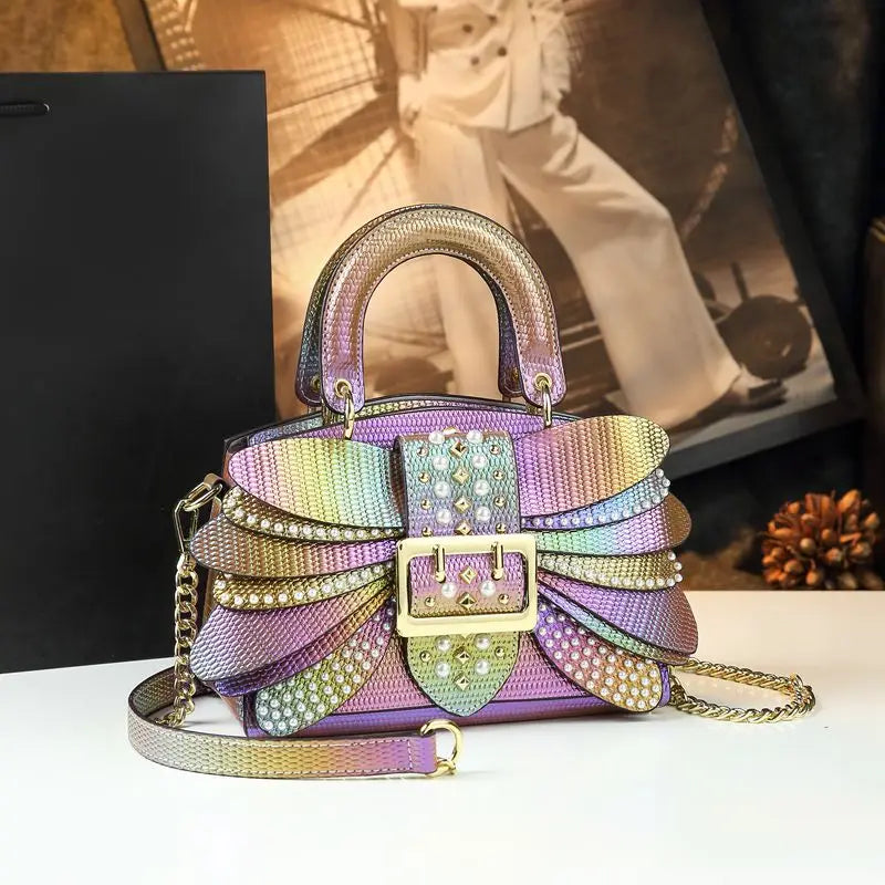 Multicolored handbag with rhinestone details on a white surface. Women’s pearl riveted leather bag—animal print, trapezoid box shape, shoulder/crossbody style, soft handle, stylish UK fashion messenger handbag.