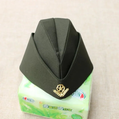 Black hat with a gold emblem on a green tissue box against a beige background