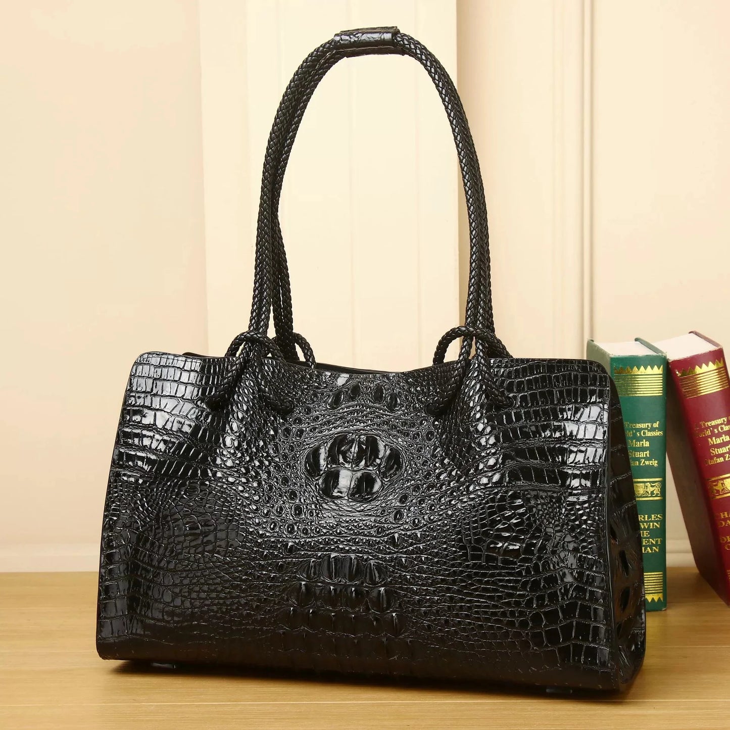 Black crocodile-patterned handbag on a wooden surface with books in the background. Luxury women’s tote bag in genuine red crocodile leather. Large capacity, stylish handle, fashion travel handbag. Perfect for shoulder or portable use UK.