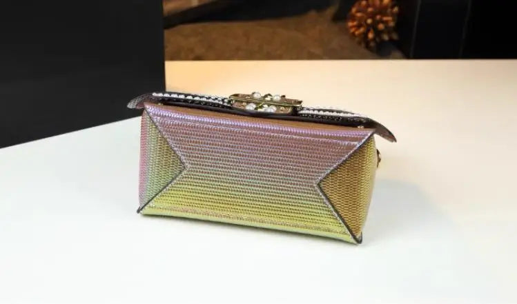 Multicolored clutch bag on a white surface with a blurred background. Women’s pearl riveted leather bag—animal print, trapezoid box shape, shoulder/crossbody style, soft handle, stylish UK fashion messenger handbag.