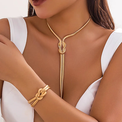 Gold necklace and bracelet set on a model wearing a white top. Women’s vintage goth snake twisted chain necklace & bracelet set with tassel, Y2K style jewelry accessories for fashion-forward looks.