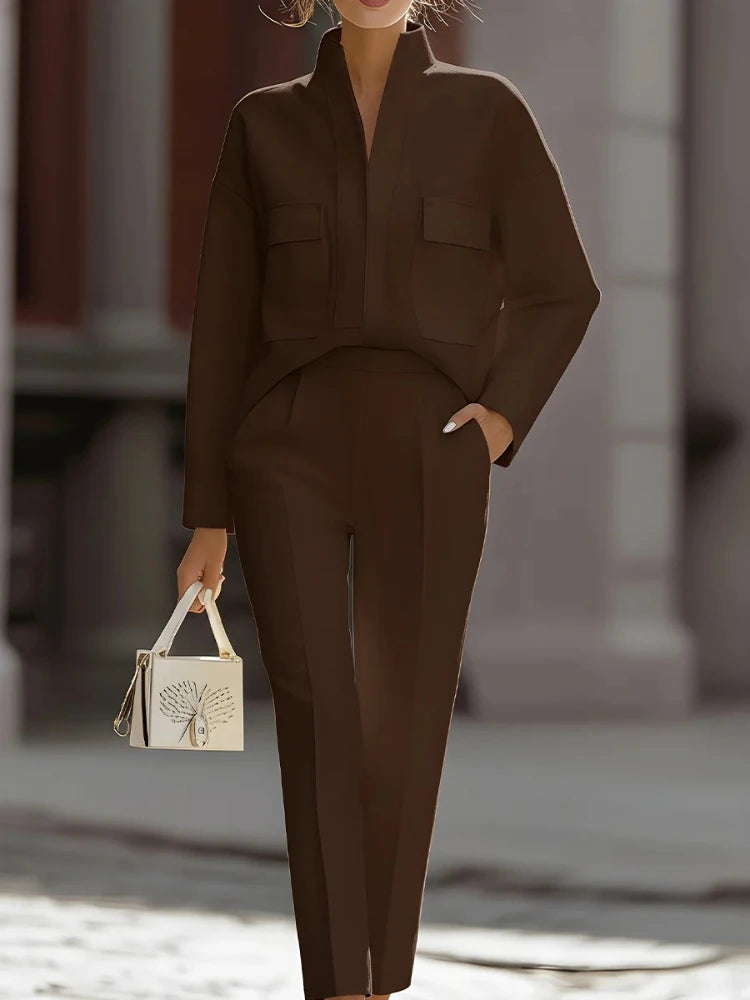 Person wearing a brown outfit holding a small handbag in an urban setting