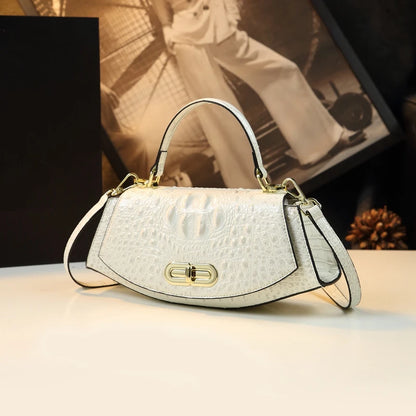White handbag with gold accents on a light surface, blurred background